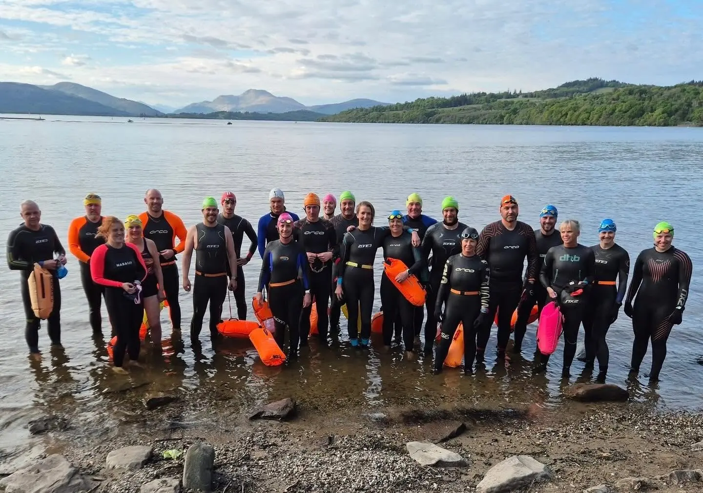 A large group of Lomond open-water swimmers standing in Loch Lomond